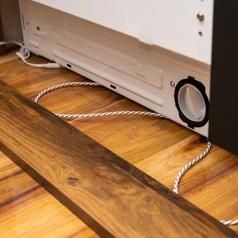 Cable sensor de fugas colocado bajo un electrodoméstico para detectar agua