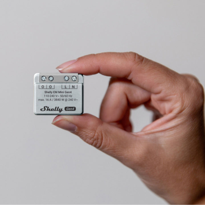 Shelly EM Mini Gen4 sostenido en la mano, medidor de energía de 13 gramos para caja de mecanismo